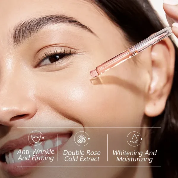 Close-up of an individual's hand holding a glass dropper next to an ear, applying serum or oil to the skin.