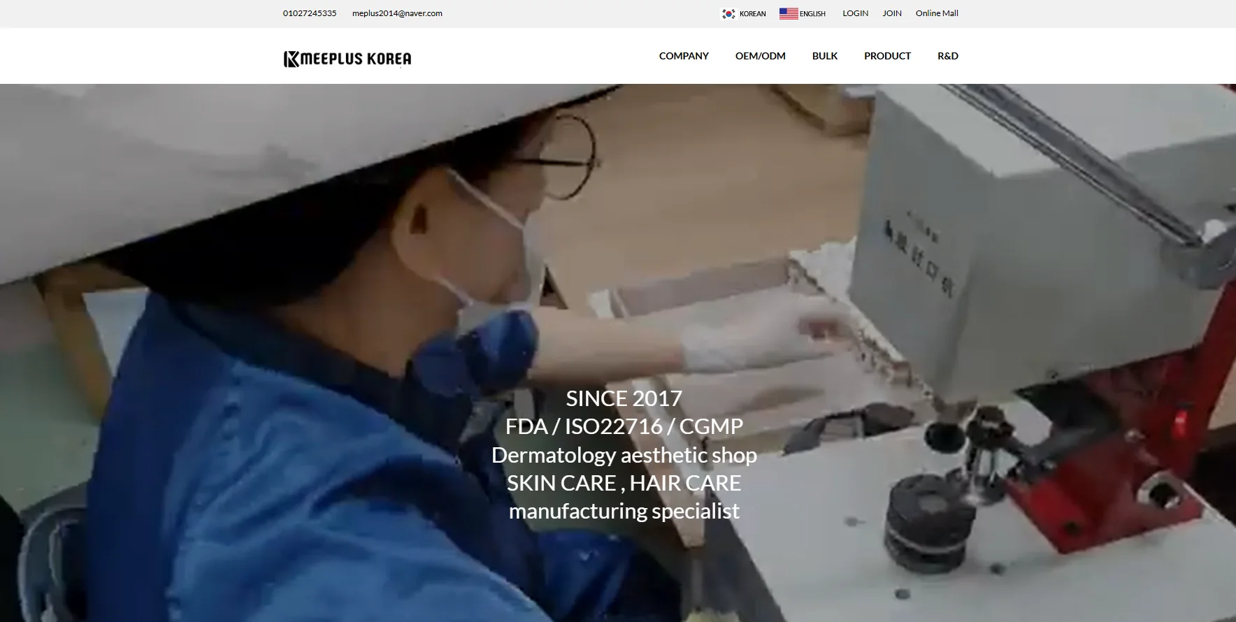 Person in blue attire operating a machine for cosmetic packaging in a manufacturing facility.