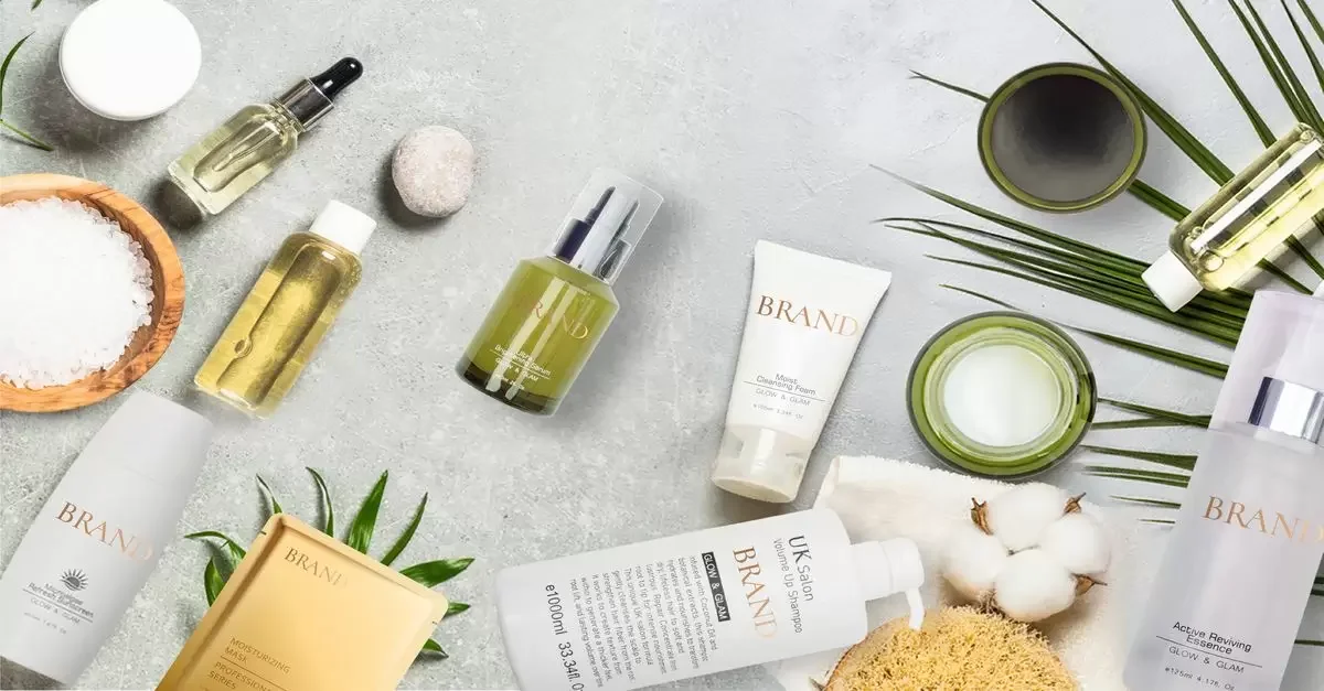 Various skincare products and accessories on a textured surface, including bottles, tubes, and natural elements such as cotton and leaves.