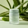 A jar of botanical clarity facial cream set against an aloe plant background, featuring soothing repair properties.
