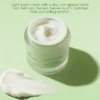 Botanical clarity facial cream in a jar with creamy texture spread beside it, placed on a light green background with text about its benefits.