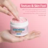 Hand holding a jar of rice cake cleanser with a finger dipping into its soft pink texture against a pastel pink background.