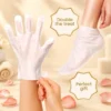 Close-up of a hand wearing a moisturizing glove with a foot mask nearby, surrounded by petals and spa decor.