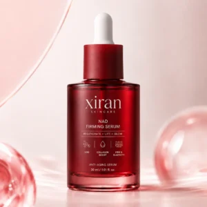 Xiran NAD Firming Serum in a sleek red bottle with white dropper, shown against a soft pink background. The product highlights anti-aging and skin firming benefits.