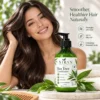 A smiling woman with silky brown hair showcasing a bottle of Xiran Tea Tree Conditioner surrounded by green leaves, promoting natural haircare benefits.