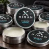 Xiran men's grooming firm hold pomade tins displayed on a wooden surface with close-up of an open container showing the product texture.